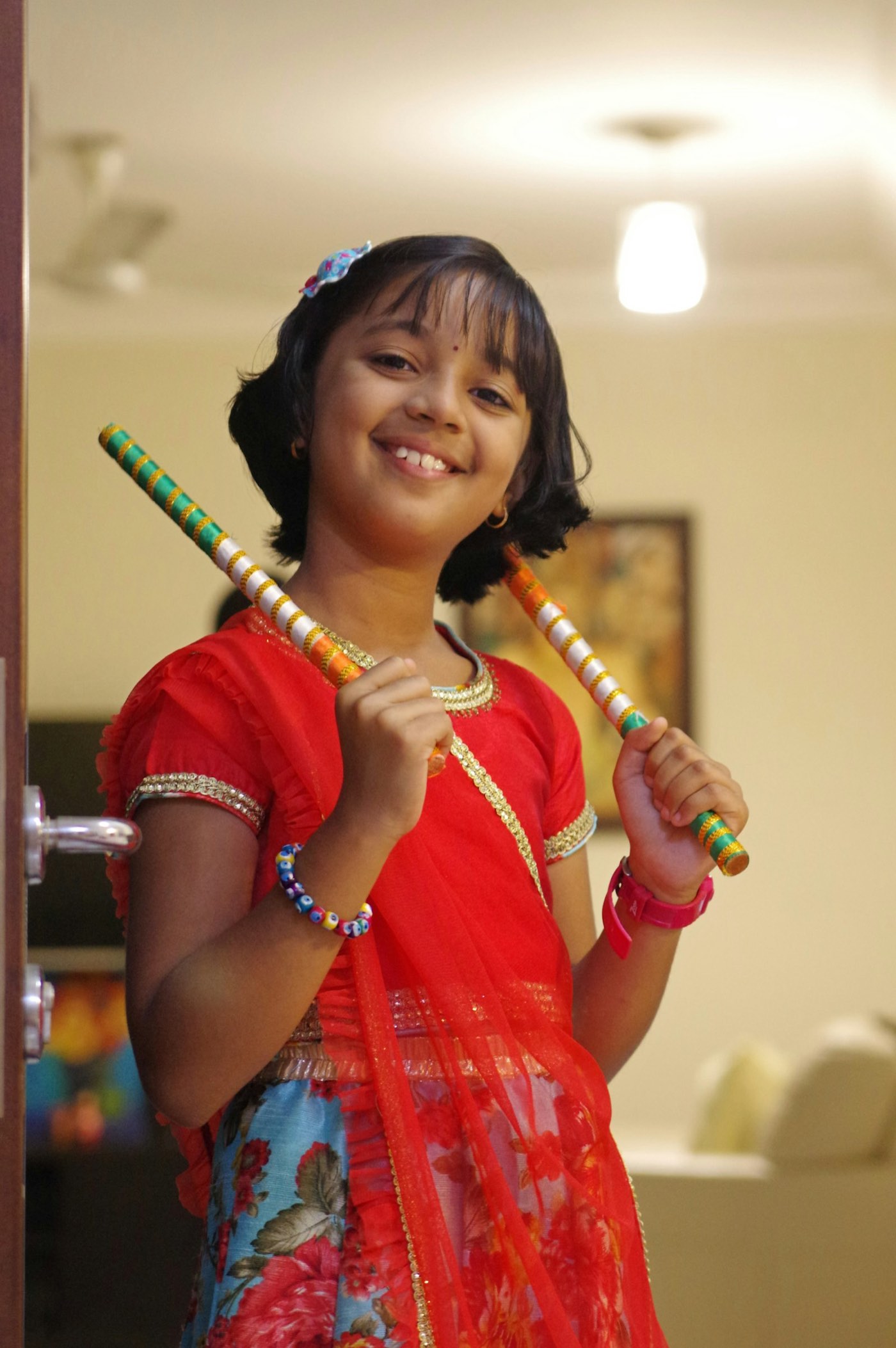 A young dancer holding dandiya sticks in traditional dress